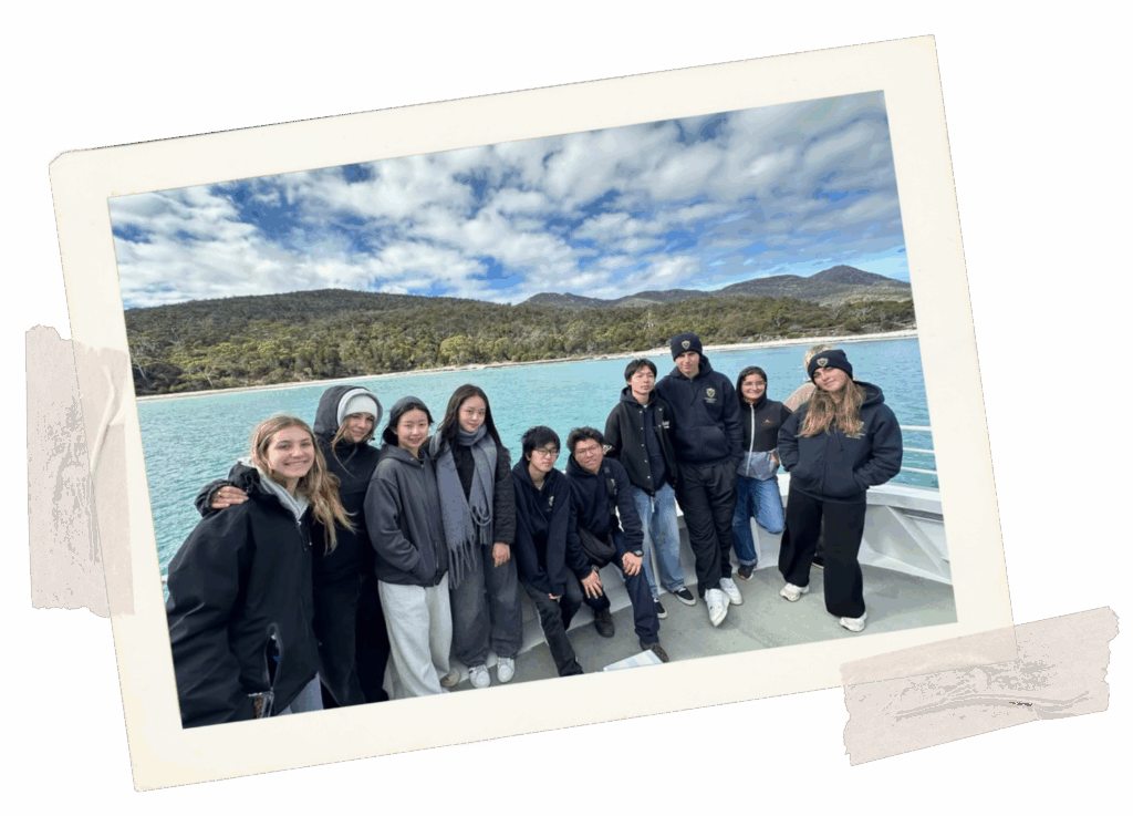 Group of teens outside on a boat, appears to be a cold day out on the water.