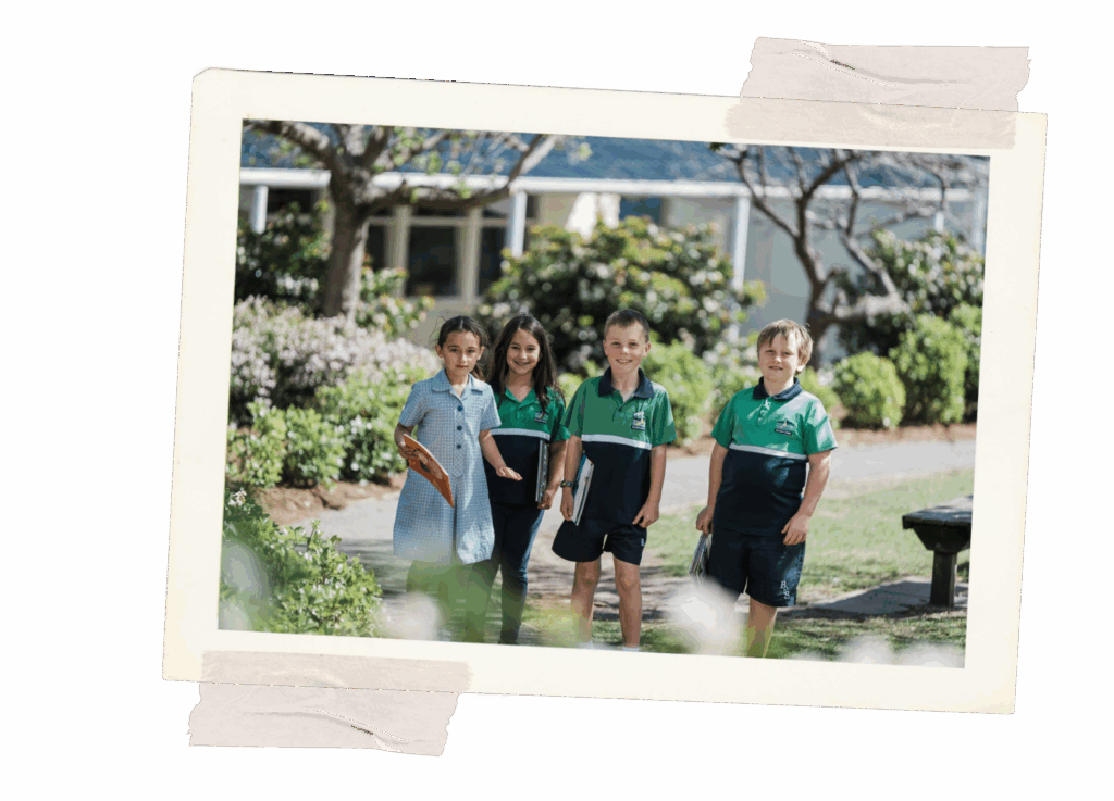 Four young child standing amongst trees and bushes smiling, they have books.