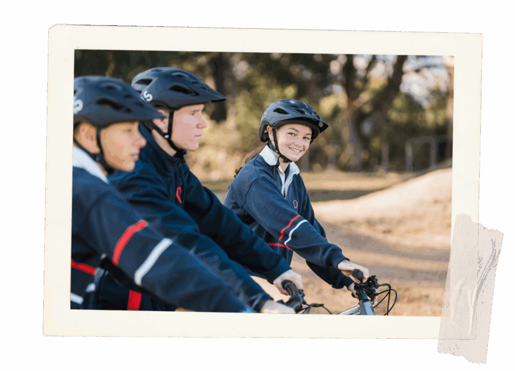 Three teens about to ride their bikes. One of the teens is smiling.